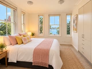 Bright bedroom with tall windows looking out to the harbour